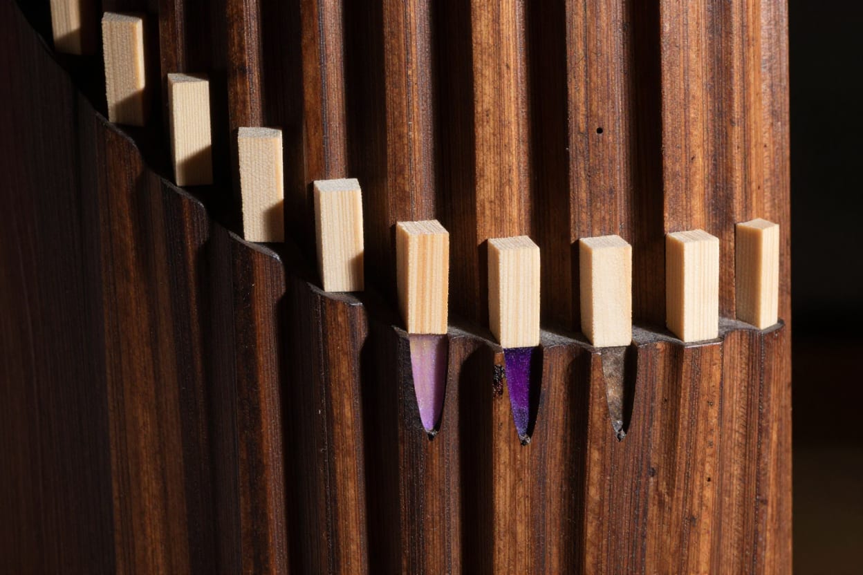 A column of carved register slots filled with maple plugs